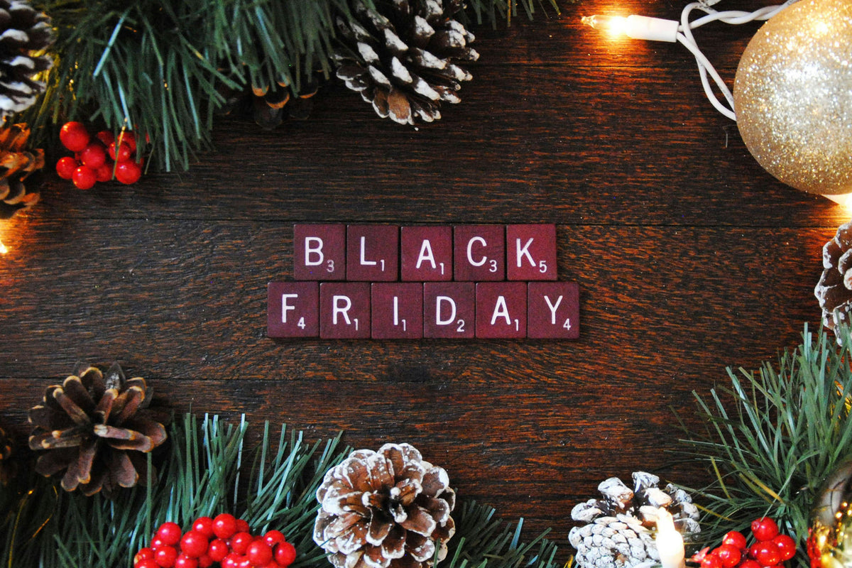 Tiles spelling out "Black Friday," surrounded by pine cones and Christmas decorations
