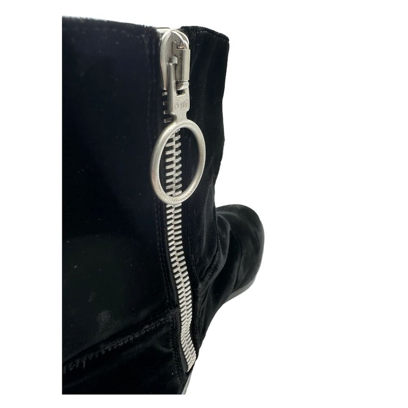 Black Calfskin Women Ankle BootUnleash enviable chic with these statement Off-White ankle boots, masterfully crafted from premium suede calfskin. Infused with the brand’s signature edge, they feature a sleek side zip opening for easy wear and a bold logo