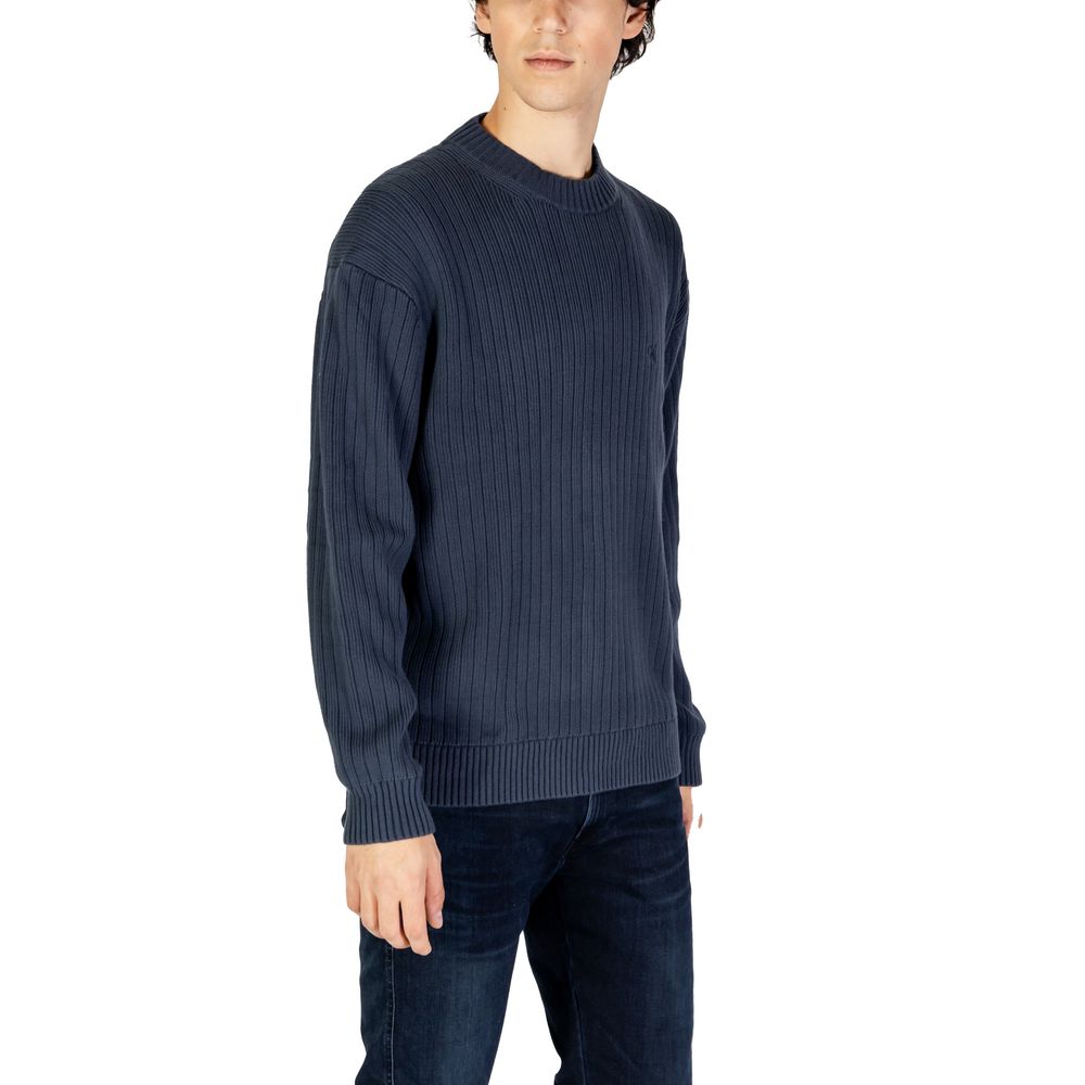 Blue Cotton SweaterThe Calvin Klein Jeans LINEAR J30J326193 men’s sweater is a must-have knitwear piece, combining contemporary style with comfort. Crafted from 100% pure cotton, it provides a soft and pleasant feel against the skin, making it ideal for t