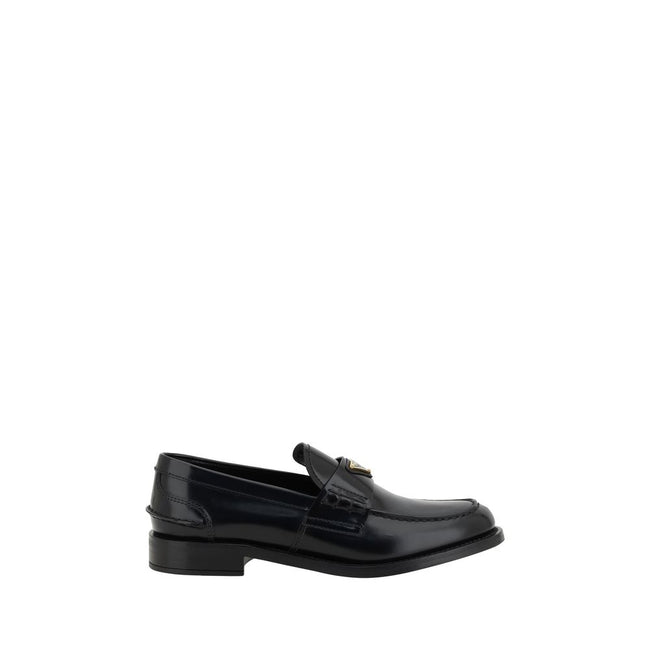 Black Leather Logo LoafersPrada’s Leather Loafers are a mix of classic elegance and distinctive details. The slightly elongated round toe and leather block heel ensure comfort and style. The iconic enameled triangular plaque with the brand’s signature app
