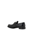 Black Leather Logo LoafersPrada’s Leather Loafers are a mix of classic elegance and distinctive details. The slightly elongated round toe and leather block heel ensure comfort and style. The iconic enameled triangular plaque with the brand’s signature app