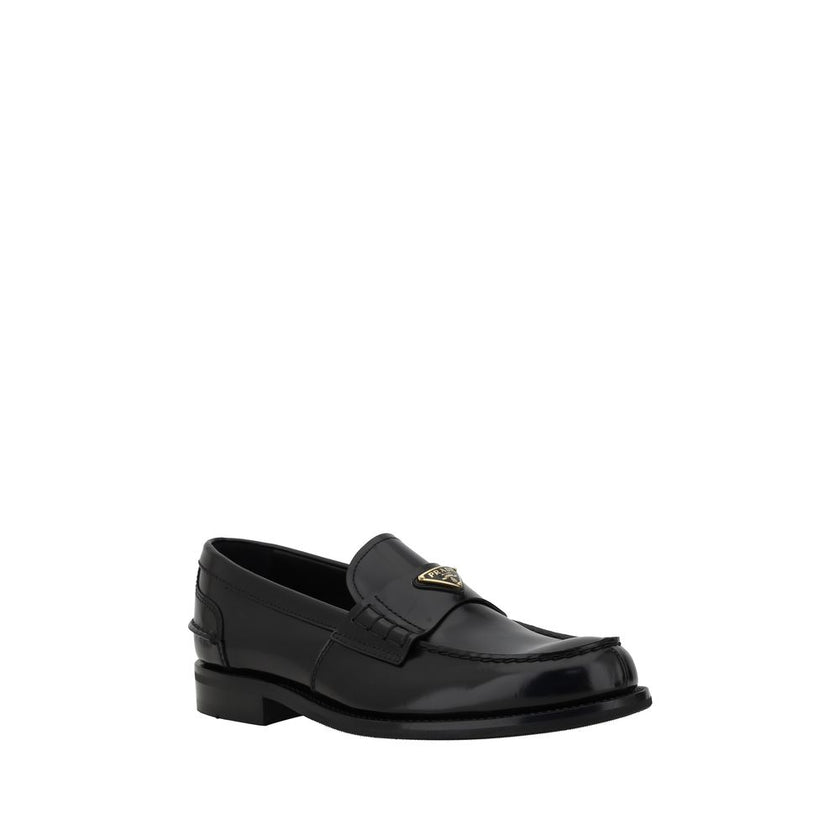 Black Calf Leather Bos Taurus Slip-On LoafersPrada’s leather Loafers are a mix of classic elegance and distinctive details. The slightly elongated round toe and leather block heel ensure comfort and style. The iconic enameled triangular plaque with the br