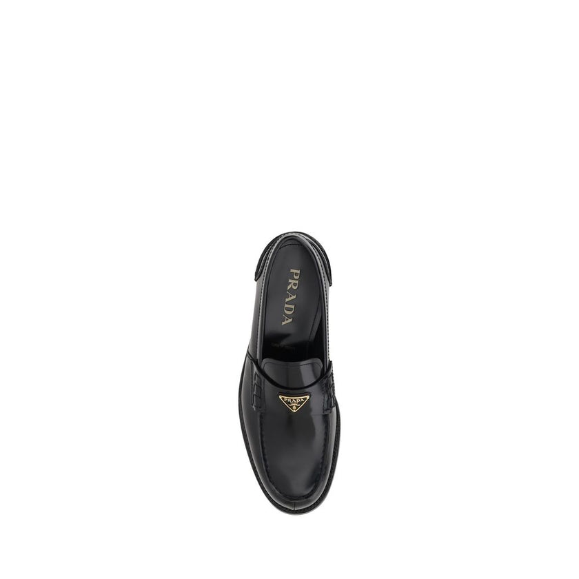 Black Calf Leather Bos Taurus Slip-On LoafersPrada’s leather Loafers are a mix of classic elegance and distinctive details. The slightly elongated round toe and leather block heel ensure comfort and style. The iconic enameled triangular plaque with the br