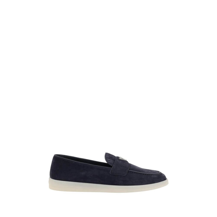 Blue Rubber Slip-On LoafersPrada’s leather Loafers feature an almond toe and a suede design that lends a touch of sophisticated elegance. The contrasting flat sole and front tray embellished with the brand’s iconic triangular plaque add a distinctive deta