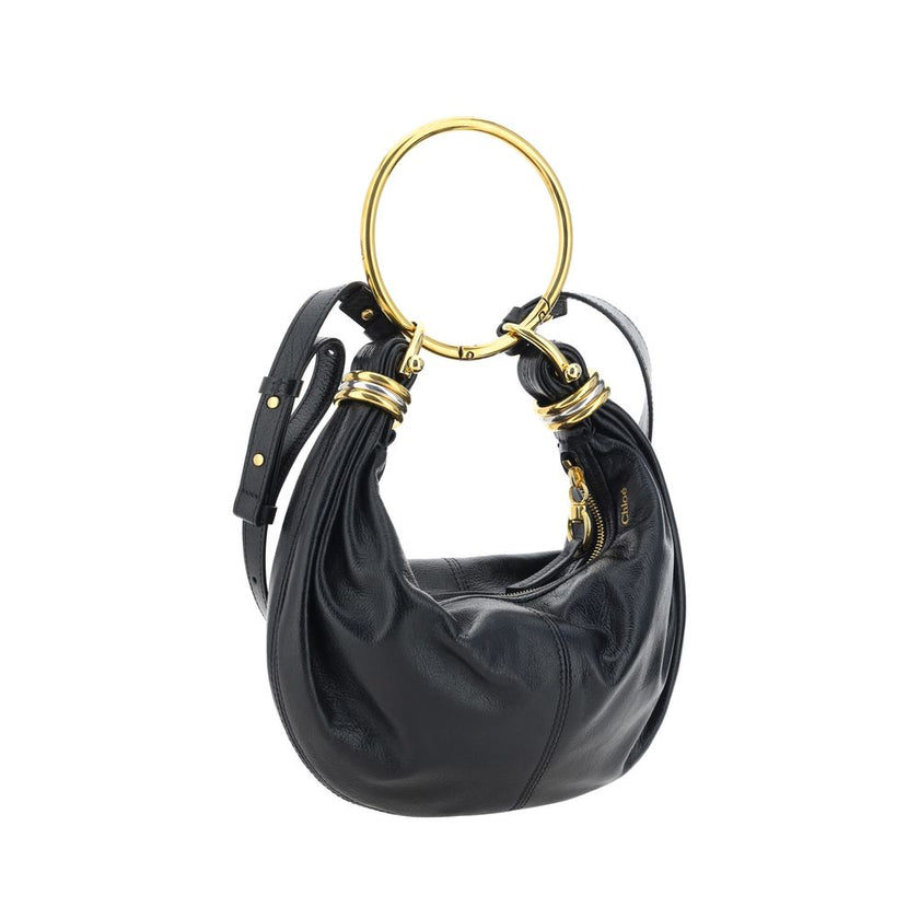 Black Calf Leather Bos Taurus HandbagLeather Bracelet Handbag by Chloé, a round brass handle, an adjustable flat shoulder strap and removable top zipper closure, single interior compartment. Season: AW25 Dimension: 32x32x10 Composition: 100% Calf Leather