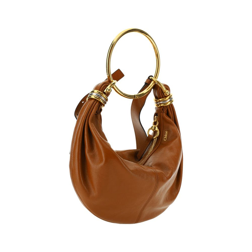 Brown Calf Leather Bos Taurus HandbagLeather Bracelet Handbag by Chloé, a round brass handle, an adjustable flat shoulder strap and removable top zipper closure, single interior compartment. Season: AW25 Dimension: 32x32x10 Composition: 100% Calf Leather