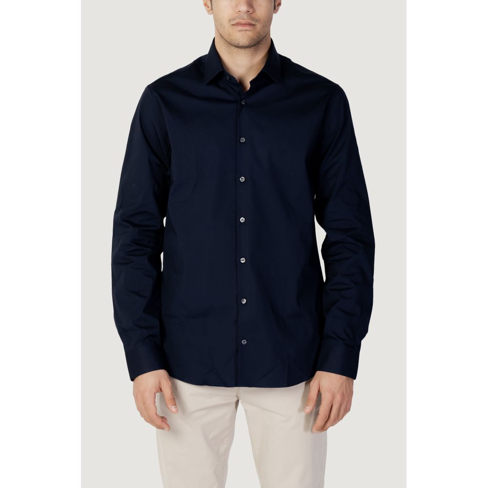 Blue Cotton Dress ShirtDiscover the long-sleeve men’s shirt by Calvin Klein, model POPLIN STRETCH SLIM. Made with a composition of 96% cotton and 4% elastane/lycra, this shirt offers exceptional comfort and a slim fit that enhances the male silhouette. Pe