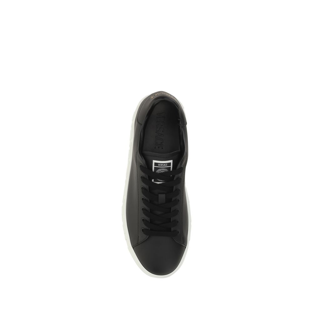 Black Rubber Low Top SneakersCalfskin Sneakers by Versace, featuring round toe, front lace-up closure, flat sole with iconic Greek embossed print, iconic monogram stamped press-stamped on back, press-stamped logo insole. Season: AW25 Composition: SOLE 100