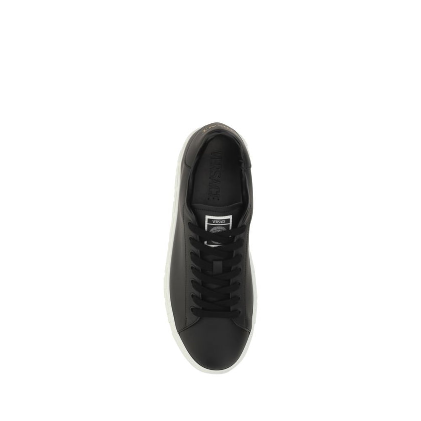 Black Rubber Low Top SneakersCalfskin Sneakers by Versace, featuring round toe, front lace-up closure, flat sole with iconic Greek embossed print, iconic monogram stamped press-stamped on back, press-stamped logo insole. Season: AW25 Composition: SOLE 100
