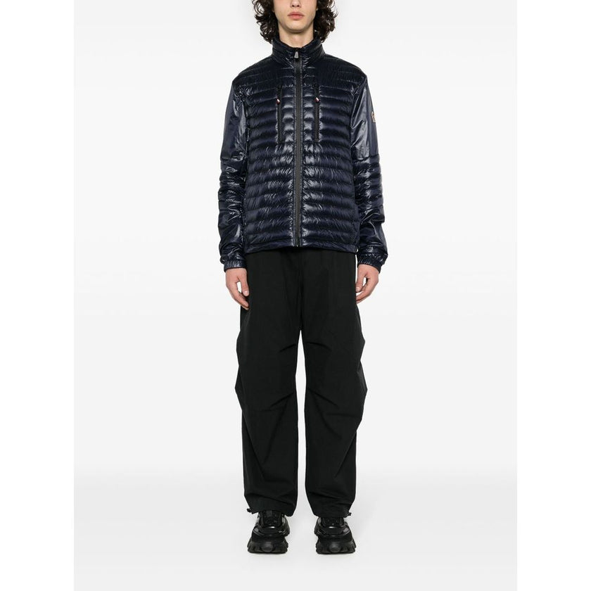 Blue Polyamide Men JacketElevate your outerwear with the Moncler Grenoble jacket, a fusion of luxe and practicality. This high-necked piece, crafted for the fashion-forward, flaunts a padded silhouette with a front zipper closure that adds an edge to any