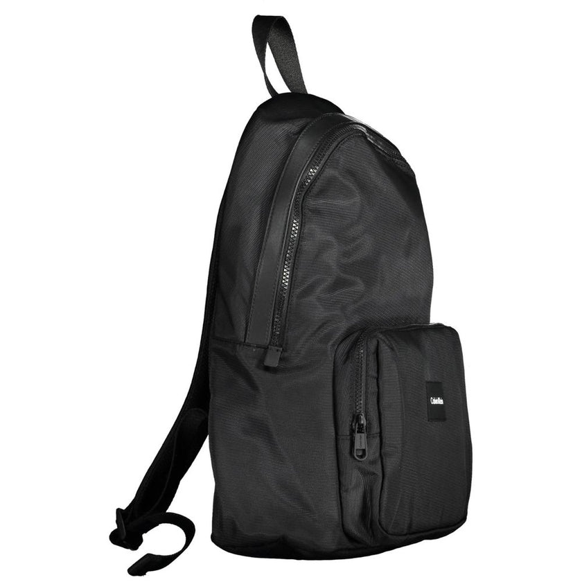 Black Polyester Men BackpackElevate your style with the sleek and sophisticated Calvin Klein backpack. Crafted for the urban trendsetter, this backpack stands out with its bold logo and contemporary design. With adjustable straps and a range of pockets, i