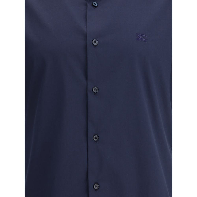 Blue Cotton Shortsleeve ShirtBurberry’s Short Sleeve Shirt combines essential elegance with iconic details. Featuring a classic collar and front button closure, it is distinguished by the iconic Equestrian Knight logo sewn on the front, which adds a touch