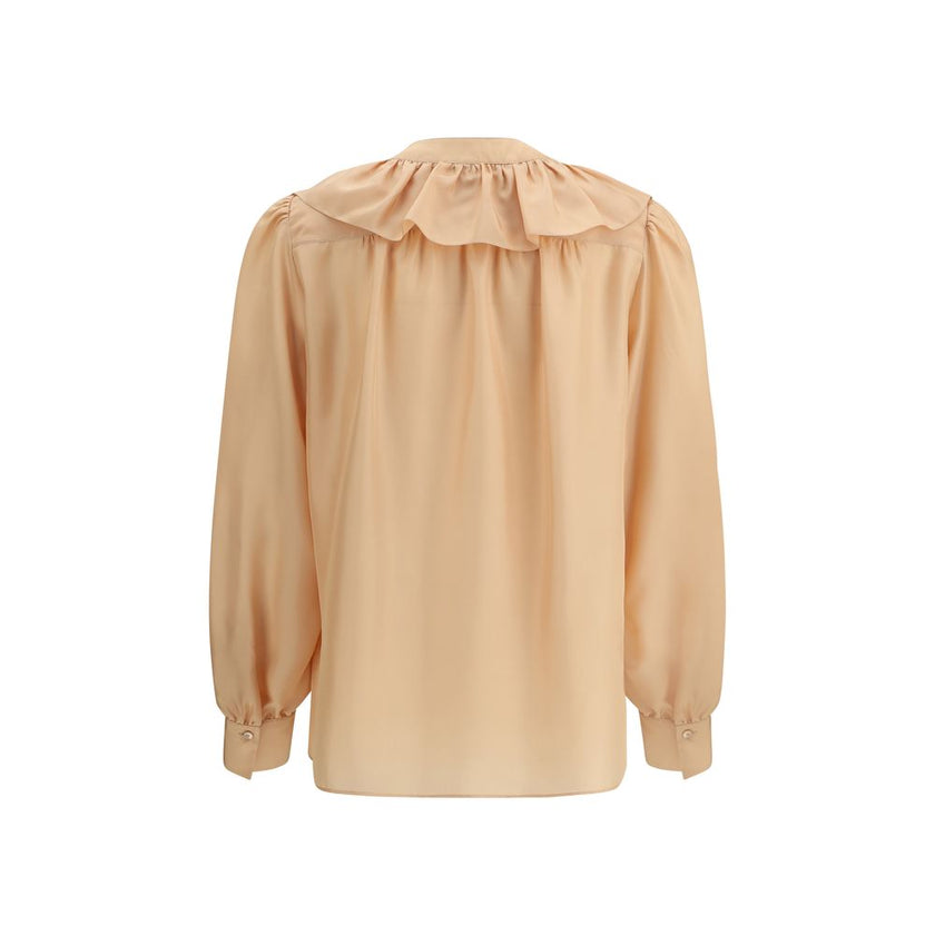 Ruffle ShirtChloé’s Habotai Silk Ruffle Shirt by Chloé is a romantic and sophisticated piece, perfect for adding an ethereal touch to your wardrobe. Featuring a V-neckline and a delicate row of ruffles on the front, it expresses femininity with lightness