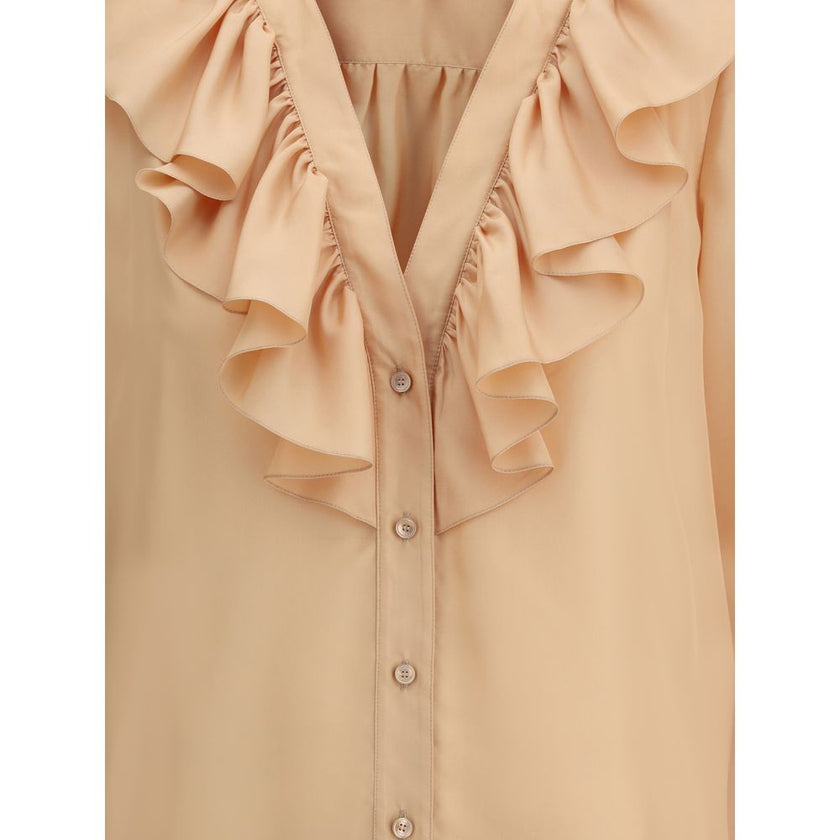 Ruffle ShirtChloé’s Habotai Silk Ruffle Shirt by Chloé is a romantic and sophisticated piece, perfect for adding an ethereal touch to your wardrobe. Featuring a V-neckline and a delicate row of ruffles on the front, it expresses femininity with lightness