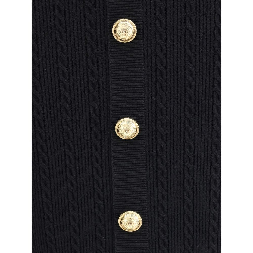 Gold Viscose Midi SkirtBalmain’s midi Skirt enhances the silhouette with a ribbed and twisted knit, giving structure and movement to the garment. On the front, the characteristic decorative 