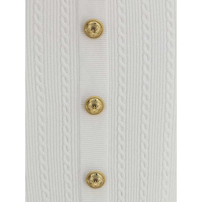 White Viscose Midi SkirtBalmain’s midi Skirt enhances the silhouette with a ribbed and twisted knit, giving structure and movement to the garment. On the front, the characteristic decorative 