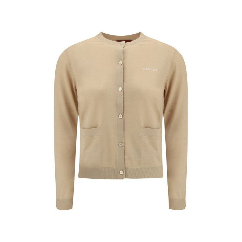 Beige Cashmere CardiganGucci’s cashmere Cardigan is a timeless garment, the epitome of elegance and comfort. Featuring a ribbed crew neck, hem and cuffs, it has a front button closure and two small patch pockets on the front. The iconic stitched signature