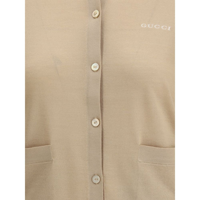Beige Cashmere CardiganGucci’s cashmere Cardigan is a timeless garment, the epitome of elegance and comfort. Featuring a ribbed crew neck, hem and cuffs, it has a front button closure and two small patch pockets on the front. The iconic stitched signature
