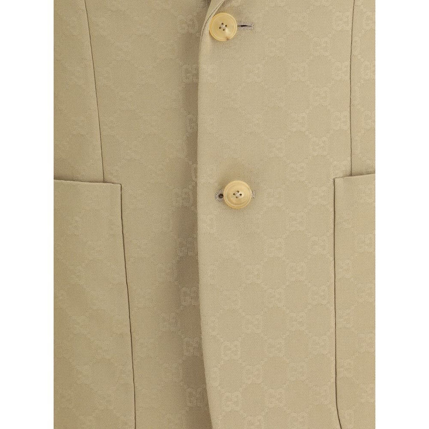 Beige Cotton BlazerGucci’s GG jacquard blazer is an elegant and distinctive piece made of jacquard fabric with the iconic GG pattern. Fully lined, it features a single-breasted button closure, notch lapels, a chest pocket and two front pockets. A perfect