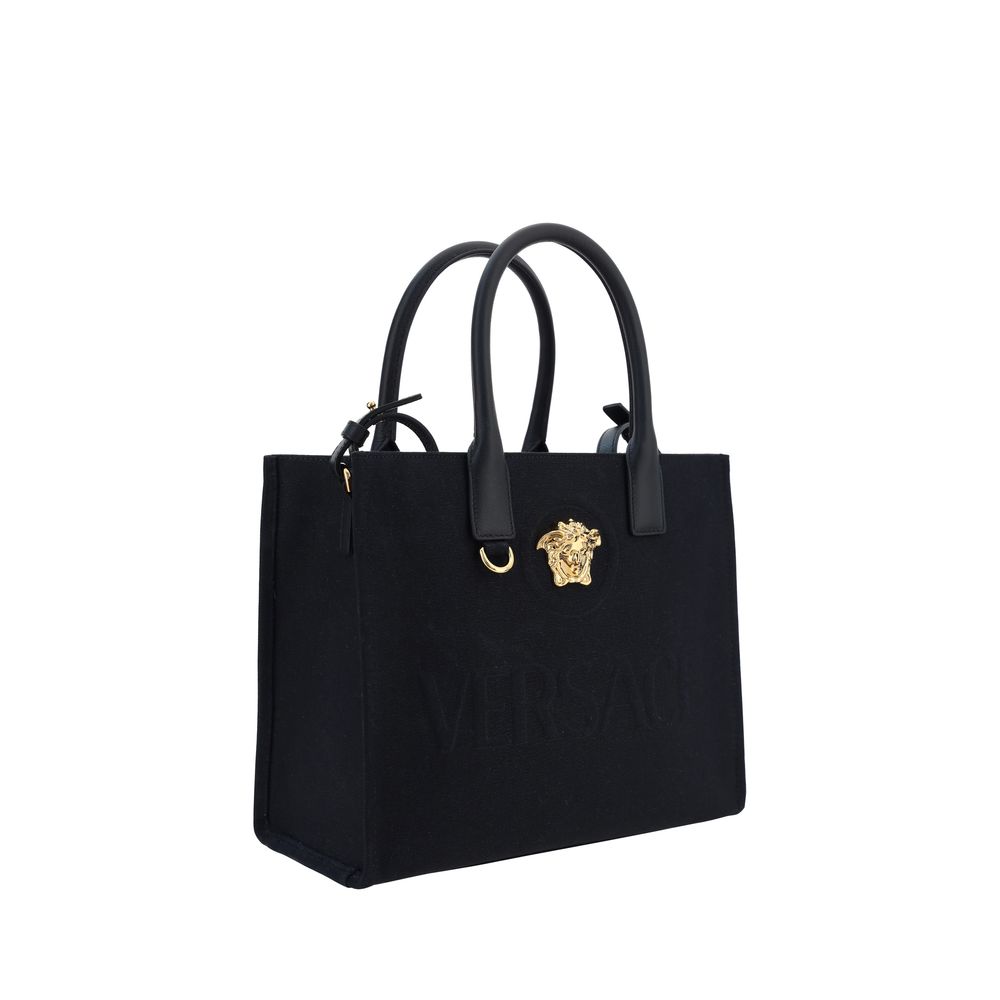Black Cotton Shoulder BagCotton Shoulder Bag by Versace, rigid leather top handles, removable flat shoulder strap, top button closure, single interior compartment, iconic brand monogram embossed on front, leather feet at base, iconic Medusa embossed appli