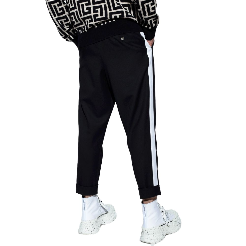 Black Cotton Men TrousersEmbark on a journey of sheer style and comfort with Balmain’s black cotton trousers. Adorned with striking white side stripes that command attention, these trousers are the epitome of modern elegance. Designed for the man who appr