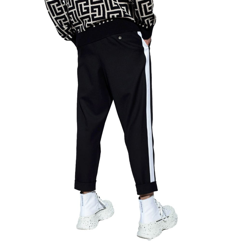 Black Cotton Men TrousersEmbark on a journey of sheer style and comfort with Balmain’s black cotton trousers. Adorned with striking white side stripes that command attention, these trousers are the epitome of modern elegance. Designed for the man who appr