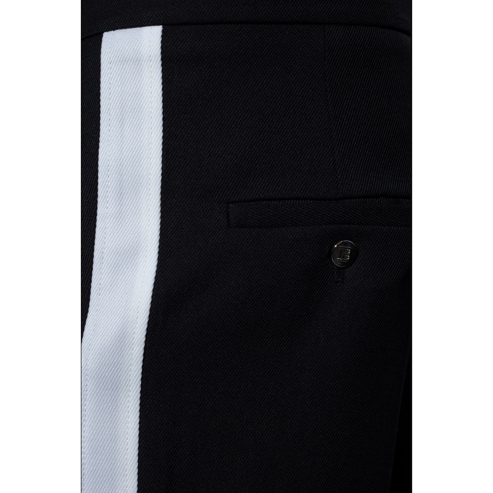 Black Cotton Men TrousersEmbark on a journey of sheer style and comfort with Balmain’s black cotton trousers. Adorned with striking white side stripes that command attention, these trousers are the epitome of modern elegance. Designed for the man who appr