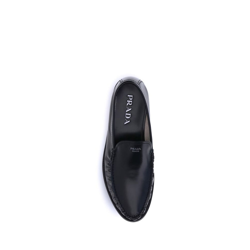 Black Calf Leather Bos Taurus Slip-On LoafersPrada’s brushed leather Loafers reinterpret a classic with a tapered, lightweight silhouette enhanced by the elegant finish of brushed leather. The refined handcrafted construction emphasizes the minimalist cha
