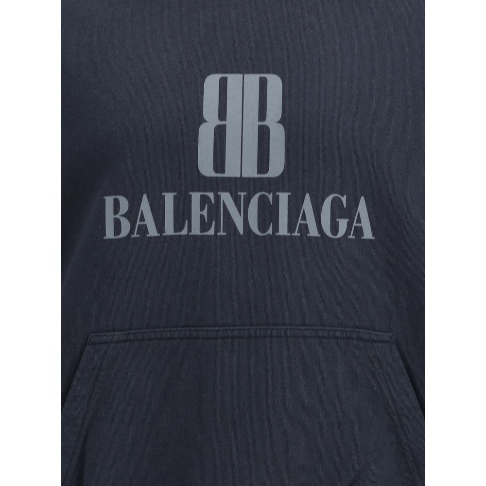Black Cotton SweatshirtBalenciaga’s Hoodie combines comfort and urban style. It features a pouch pocket on the front, the iconic contrasting printed logo, and ribbed cuffs and hem that define the relaxed fit with a touch of structure. Season: AW25 Fit: Ov