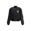 Black Polyamide BomberBalenciaga’s bomber Jacket features a zipper and pull tab closure, complemented by two flap pockets with snap buttons at the front. Ribbed edges define the garment’s profile, while a uniform chest applique adds a distinctive detail t