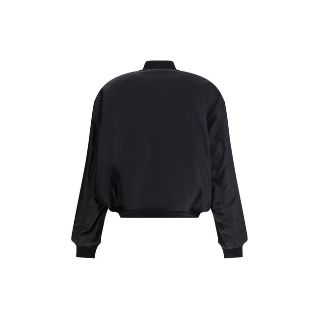 Black Polyamide BomberBalenciaga’s bomber Jacket features a zipper and pull tab closure, complemented by two flap pockets with snap buttons at the front. Ribbed edges define the garment’s profile, while a uniform chest applique adds a distinctive detail t