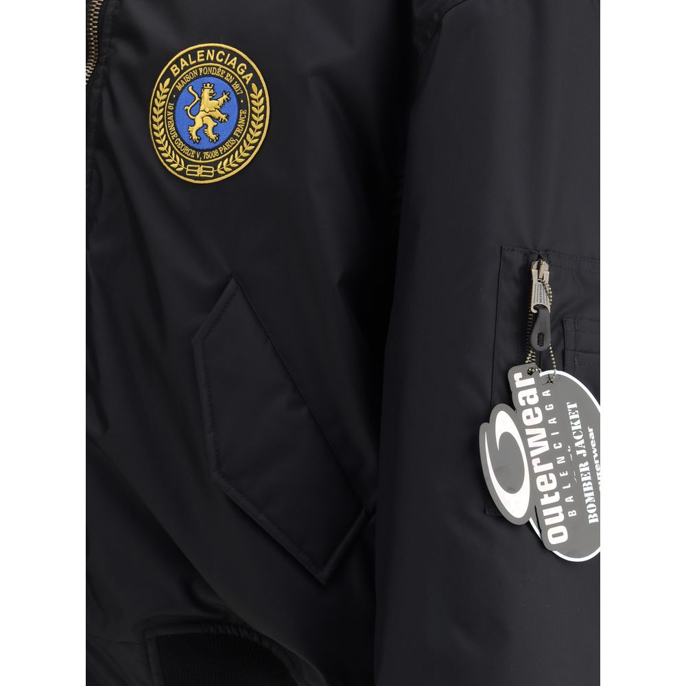 Black Polyamide BomberBalenciaga’s bomber Jacket features a zipper and pull tab closure, complemented by two flap pockets with snap buttons at the front. Ribbed edges define the garment’s profile, while a uniform chest applique adds a distinctive detail t