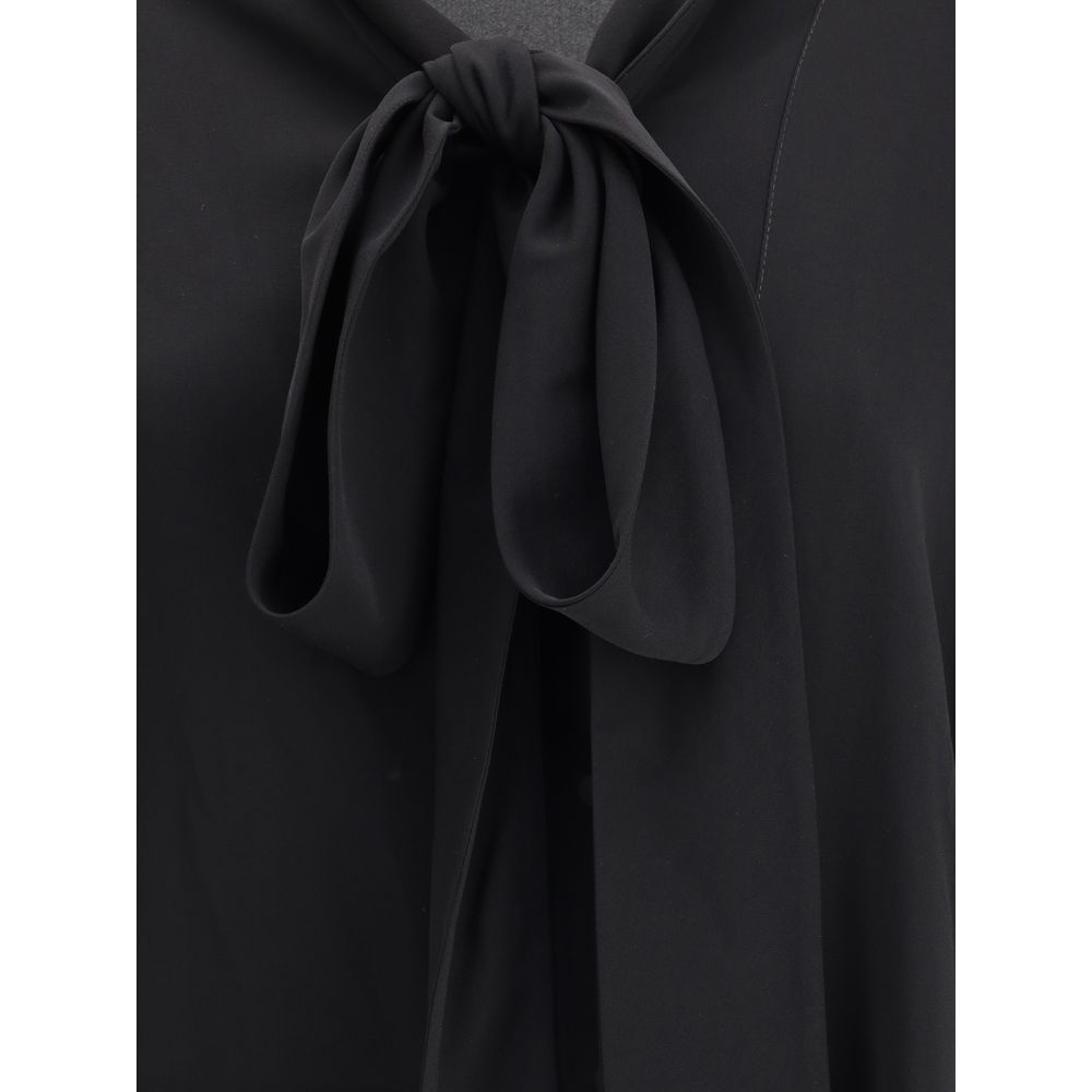 Black Silk BlouseBalenciaga’s asymmetrical Blouse is made of lightweight and fluid pure silk georgette. The sophisticated design is enriched with elegant ribbons to tie at the neck, a batwing sleeve and a long sleeve with a button-adjustable cuff. The fro