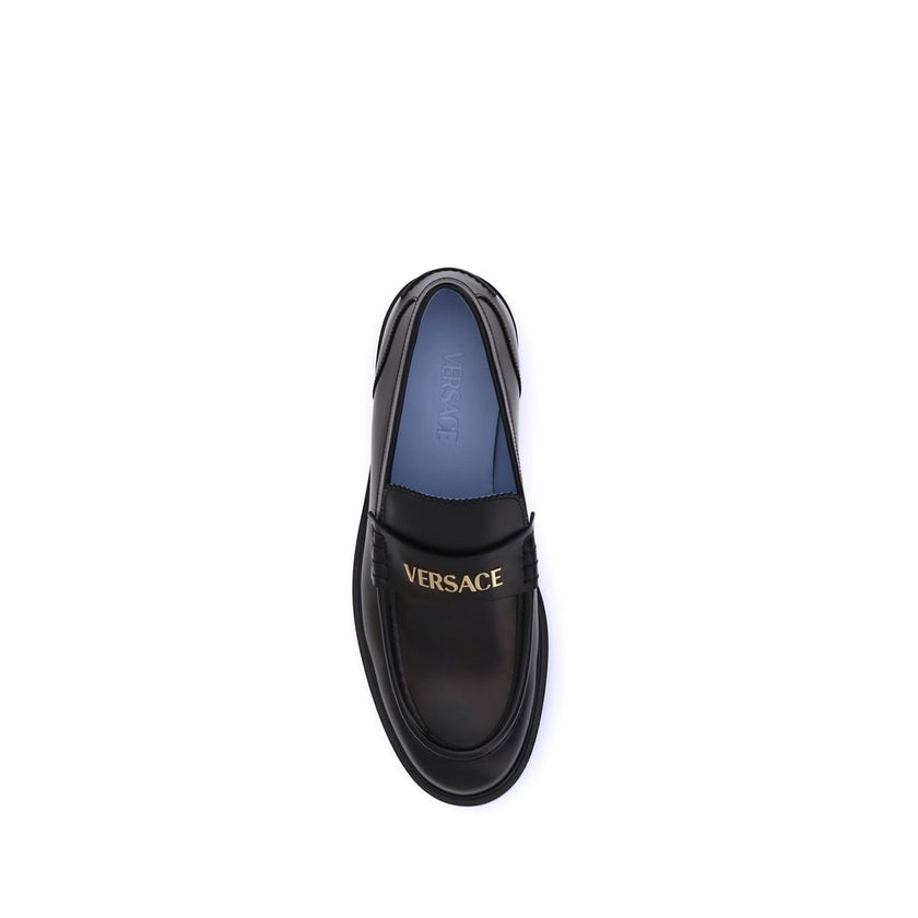 Black Calf Leather Bos Taurus Slip-On LoafersVersace’s Leather Loafers combine elegance and practicality in a slip-on design. Featuring a rounded toe, they feature the gold logo applied to the front tray, giving a distinctive and refined touch to this cla