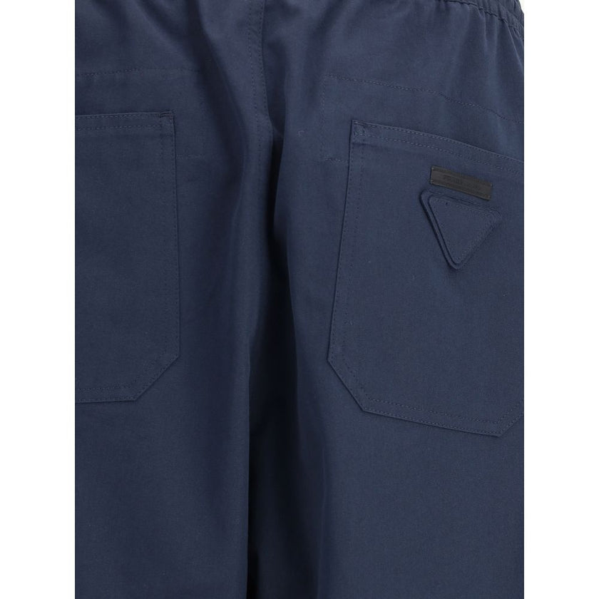 Blue Cotton Casual PantsPrada’s Cotton Pants combine comfort and style with an elasticized drawstring waistband and front zipper closure. They feature two side welt pockets and two patch pockets on the back, embellished with the iconic logo that adds a di