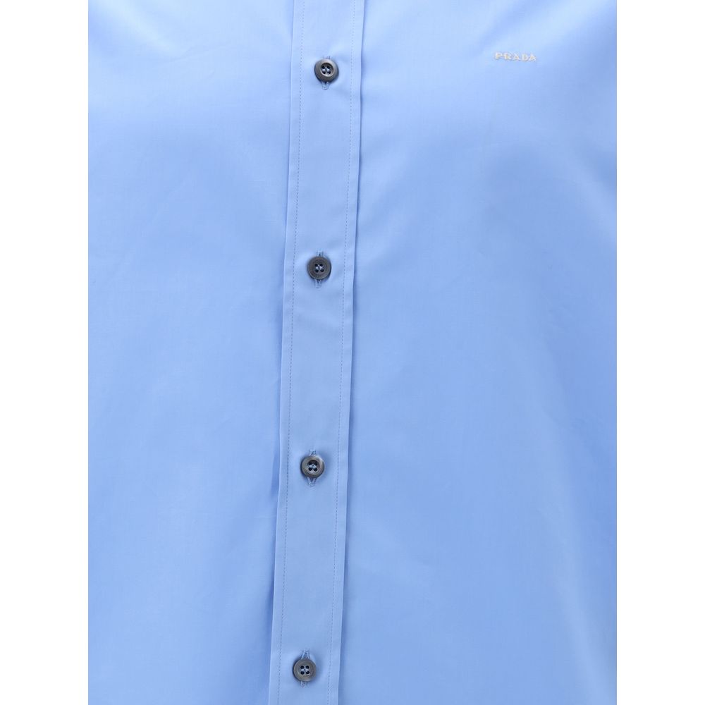 Light Blue Cotton Dress ShirtThe Prada Cotton Shirt is an essential piece with a refined style. Featuring a classic collar and front button closure, it stands out for the iconic signature sewn on the front, a discreet but unmistakable detail. Season: AW25
