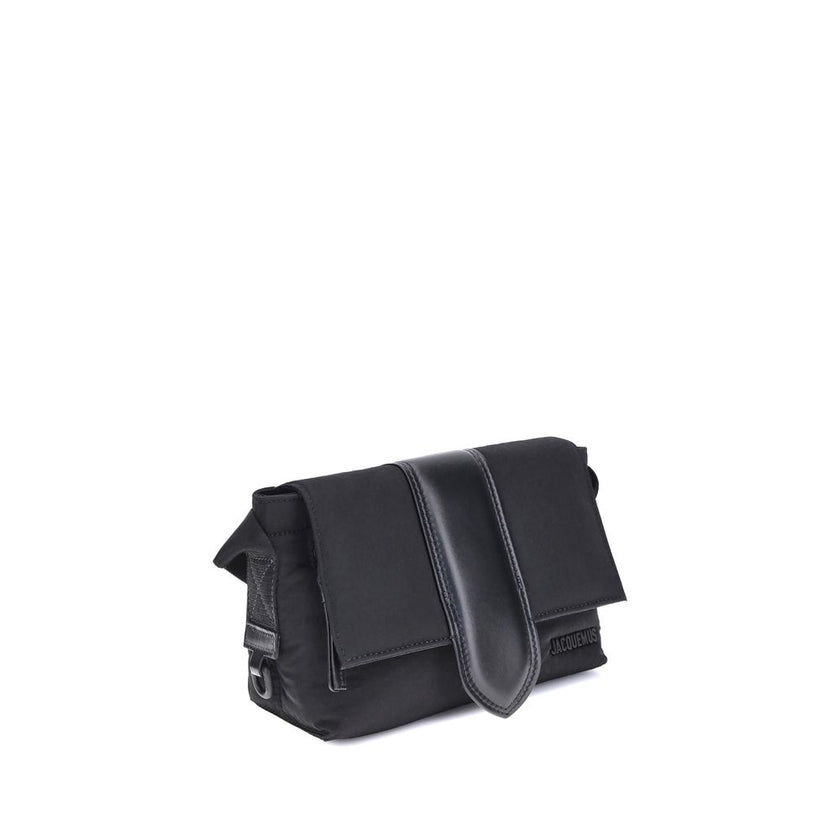 Black Nylon HandbagThe Jacquemus Nylon Bambino Shoulder Bag reinterprets the messenger style with a contemporary and functional twist. Crafted from soft nylon, it features a leather handle and a magnetic flap with a leather tab, which hides a zip closure