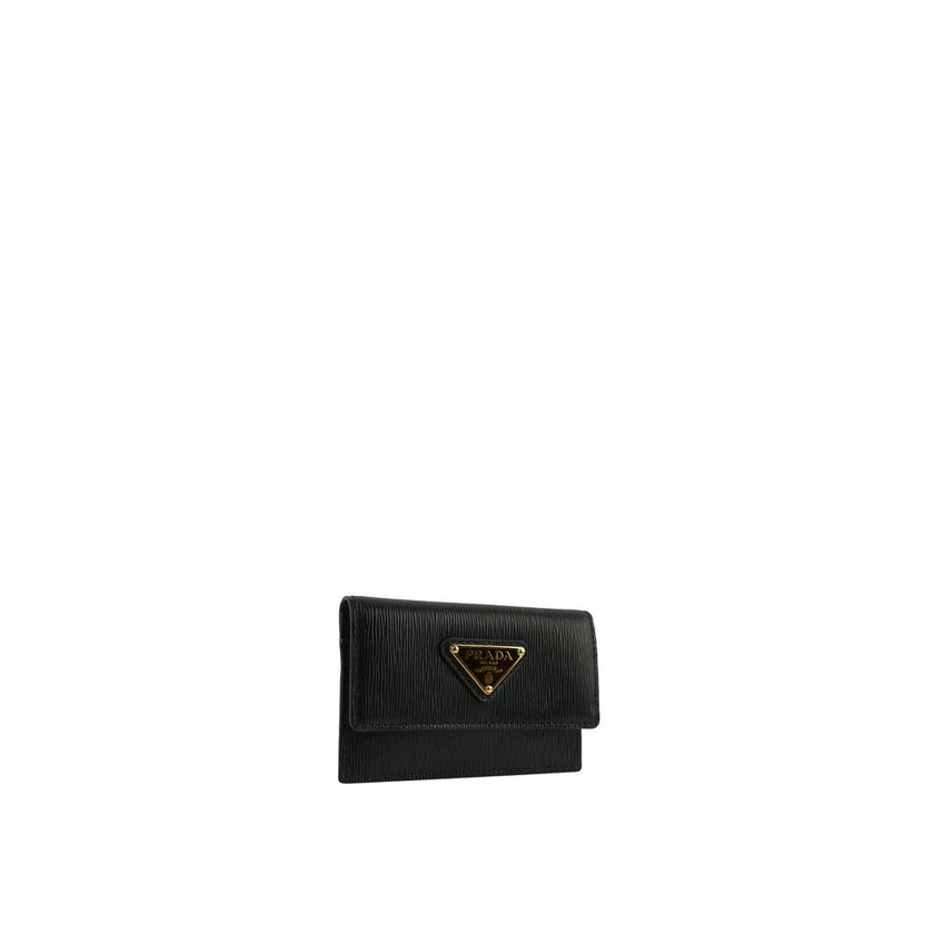Black Calfskin CardholderDescription: – Composition: 100% calf leather – height 7 cm – Width 2 cm – Length 10 cm – Two card slot – Flap top button closure – Front logo plaque – Made in Turkey – Gender: WOMEN –Black Calfskin Cardholder${tagsPradaAulae Blac