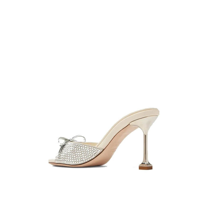 Silver Silk MulesDescription: – Composition: 100% Silk – Inner: Leather – Insole: Leather – Sole: Leather – Round toe – Open toe – Branded insole – Heel 9 cm – Open back – Crystal embellishment – Slip-on design – Top bow detail – Made in Italy – Gender: W