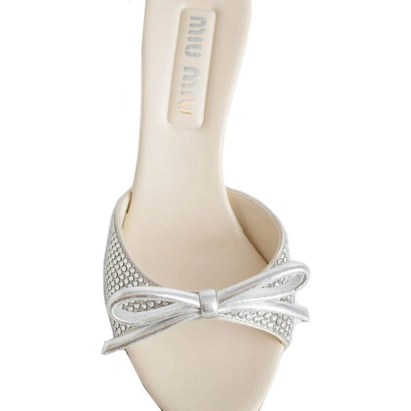 Silver Silk MulesDescription: – Composition: 100% Silk – Inner: Leather – Insole: Leather – Sole: Leather – Round toe – Open toe – Branded insole – Heel 9 cm – Open back – Crystal embellishment – Slip-on design – Top bow detail – Made in Italy – Gender: W