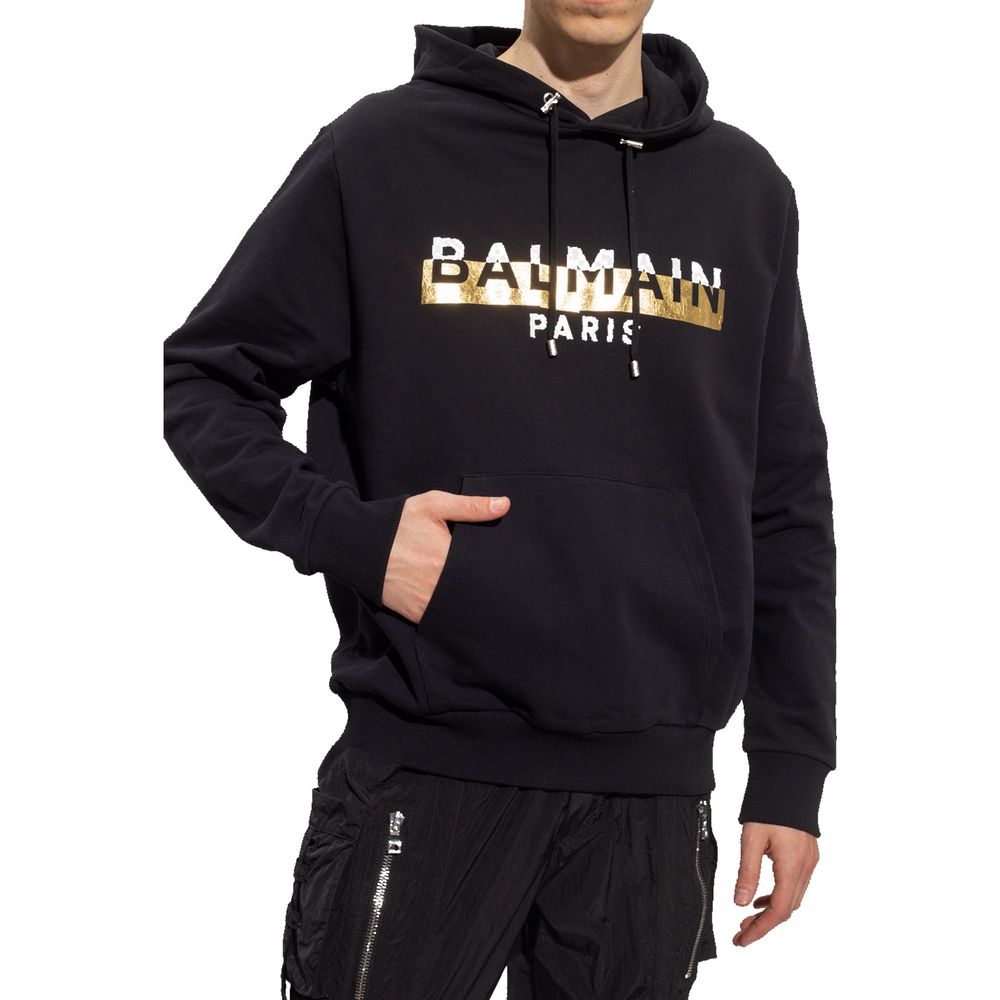 Black Cotton SweatshirtDescription: – Composition: 100% Cotton – Ribbed trims – Machine wash – Drawstring hood – Kangaroo pocket – Front logo detail – Gold-tone graphic print – Made in Italy – Gender: MEN – Size & Fit: True to size. Regular fit. Model’s M