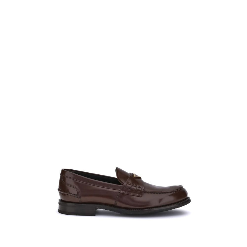 Brown Calf Leather Bos Taurus Slip-On LoafersPrada’s leather Loafers are a mix of classic elegance and distinctive details. The slightly elongated round toe and leather block heel ensure comfort and style. The iconic enameled triangular plaque with the br