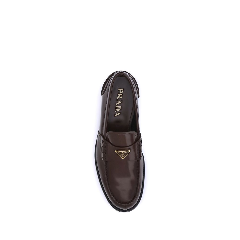 Brown Calf Leather Bos Taurus Slip-On LoafersPrada’s leather Loafers are a mix of classic elegance and distinctive details. The slightly elongated round toe and leather block heel ensure comfort and style. The iconic enameled triangular plaque with the br