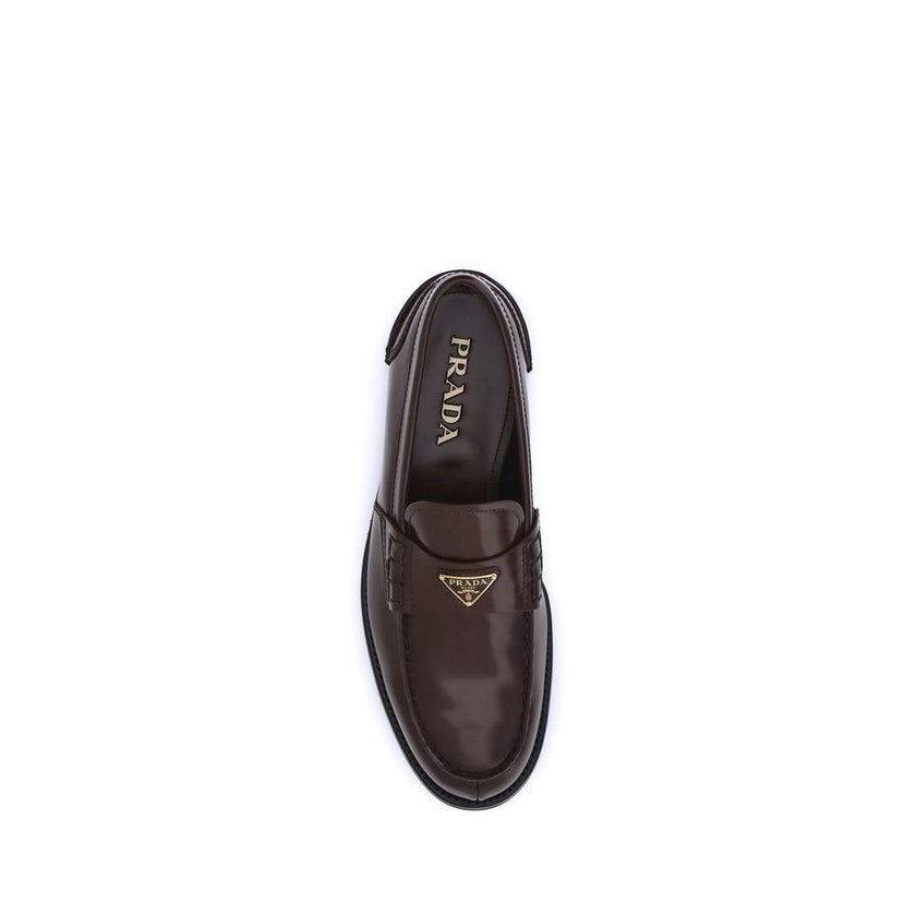 Brown Calf Leather Bos Taurus Slip-On LoafersPrada’s leather Loafers are a mix of classic elegance and distinctive details. The slightly elongated round toe and leather block heel ensure comfort and style. The iconic enameled triangular plaque with the br