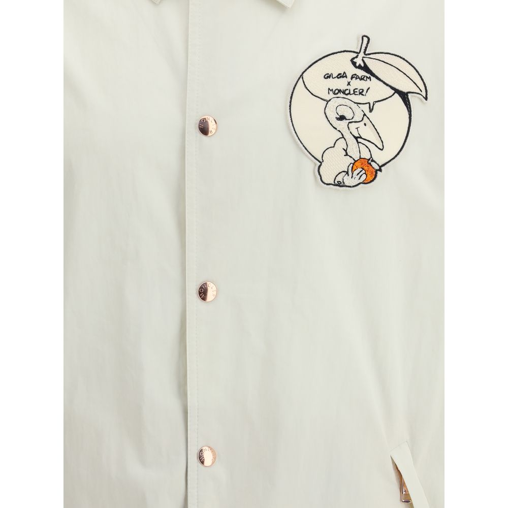 White Cotton CoatThe Moncler x Gilga Farm Satsuma Shirt Jacket by Donald Glover fuses workwear style and visual storytelling. Crafted from durable cotton and nylon canvas, it is part of the Moncler Genius line and stands out for its comic-style patches an