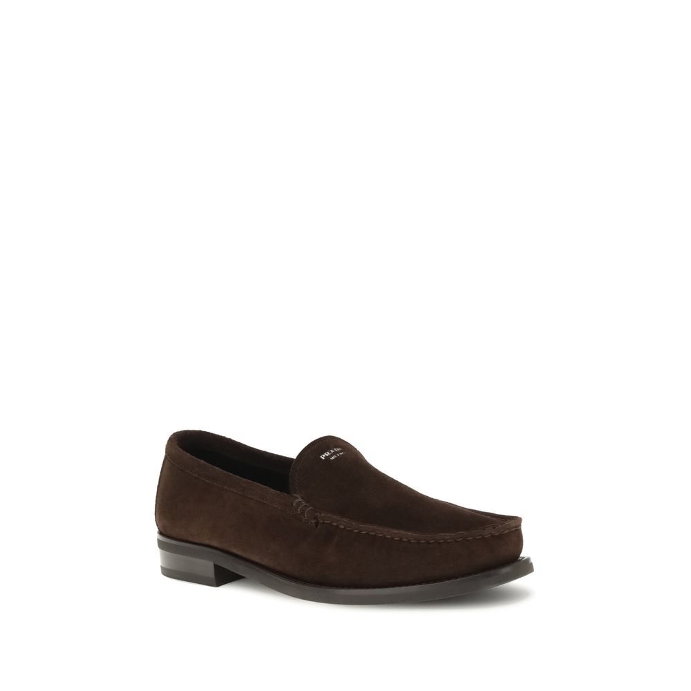 Brown Calf Leather Bos Taurus Slip-On LoafersPrada’s Suede Loafers reinterpret the classic model with a tapered, lightweight silhouette, enhanced by the refined finish of suede leather. The upper is embellished with the screen-printed logo, while the rubb