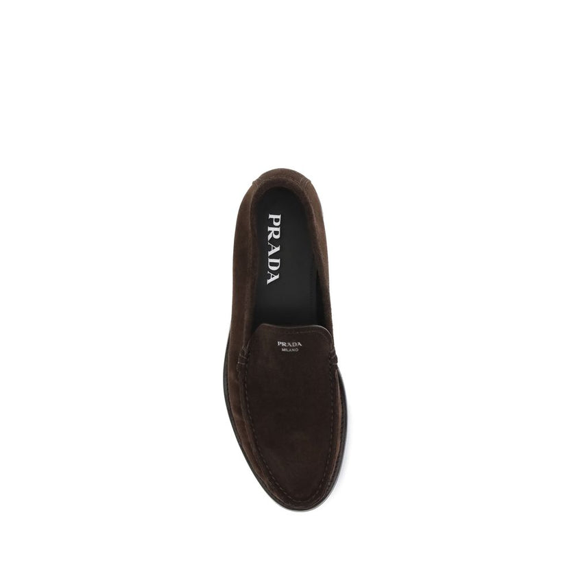 Brown Calf Leather Bos Taurus Slip-On LoafersPrada’s Suede Loafers reinterpret the classic model with a tapered, lightweight silhouette, enhanced by the refined finish of suede leather. The upper is embellished with the screen-printed logo, while the rubb
