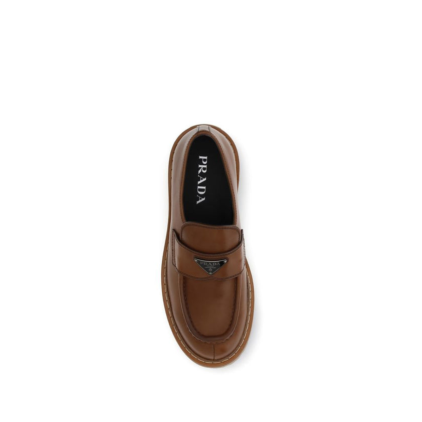 Brown Calf Leather Bos Taurus Slip-On LoafersPrada’s leather Loafers combine elegance and boldness with their patent-effect leather design, giving them a polished and sophisticated look. The rugged and durable carrarmate sole adds a touch of modernity and