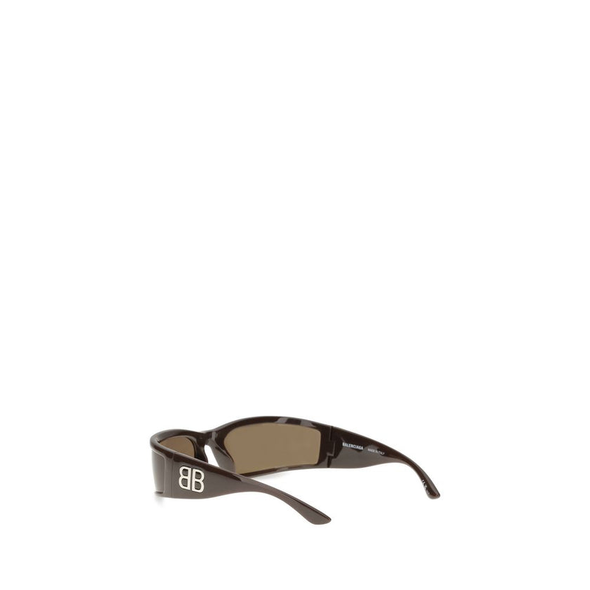 Brown Acetate SunglassesBalenciaga’s Sunset Sunglasses combine contemporary design and sustainability. Made of acetate, they are embellished with metallic logo details on the temples, adding a touch of distinctive elegance. The rectangular shape gives a m
