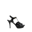 Tribute SandalsSaint Laurent’s Tribute Sandals are a timeless classic that combines elegance and boldness. Featuring a caged design on the upper, these sandals offer a sophisticated and sensual silhouette, enhanced by a patent leather finish that lends a